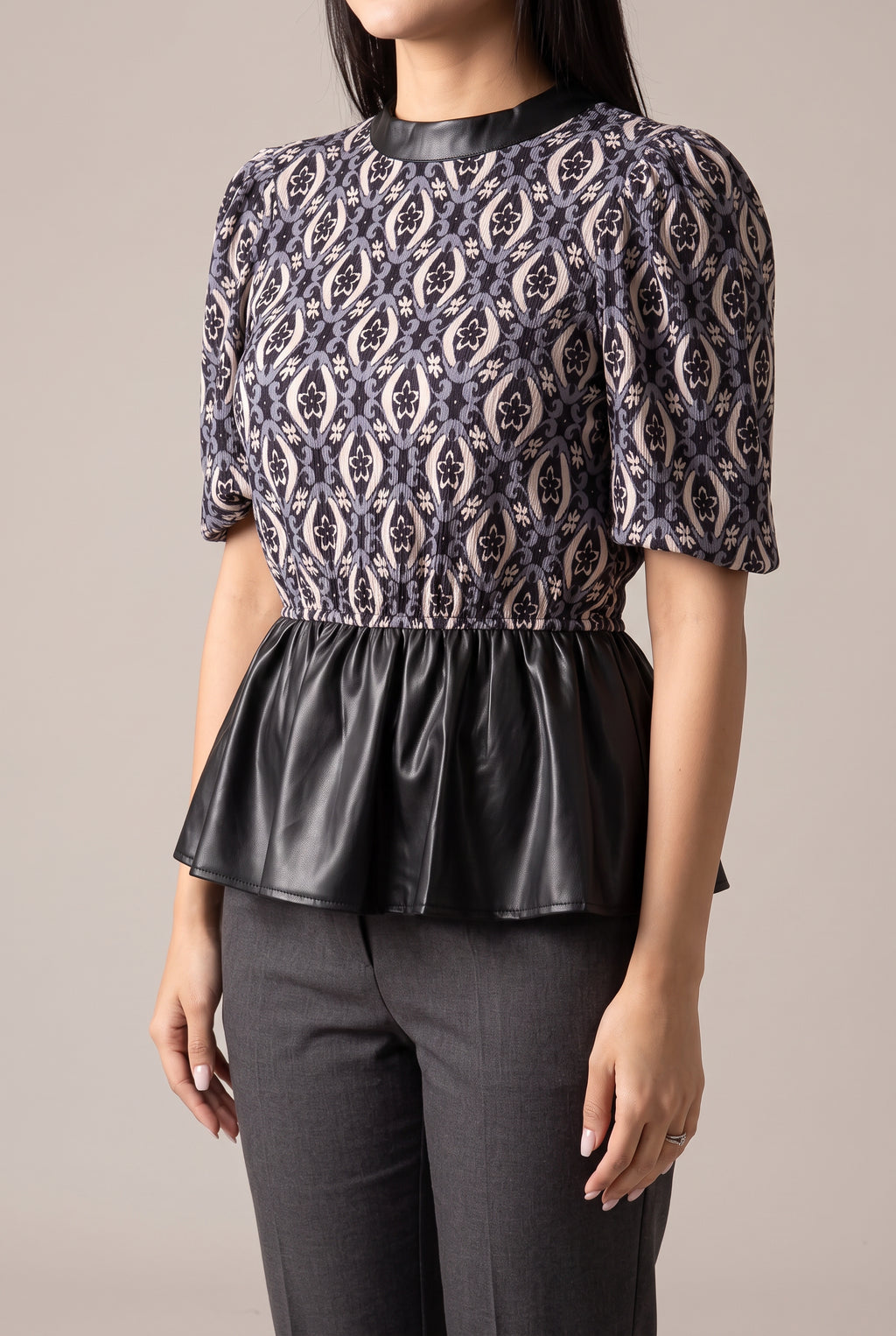Angled view of the Last Night peplum top showing its puff sleeve and projecting faux leather hem.
