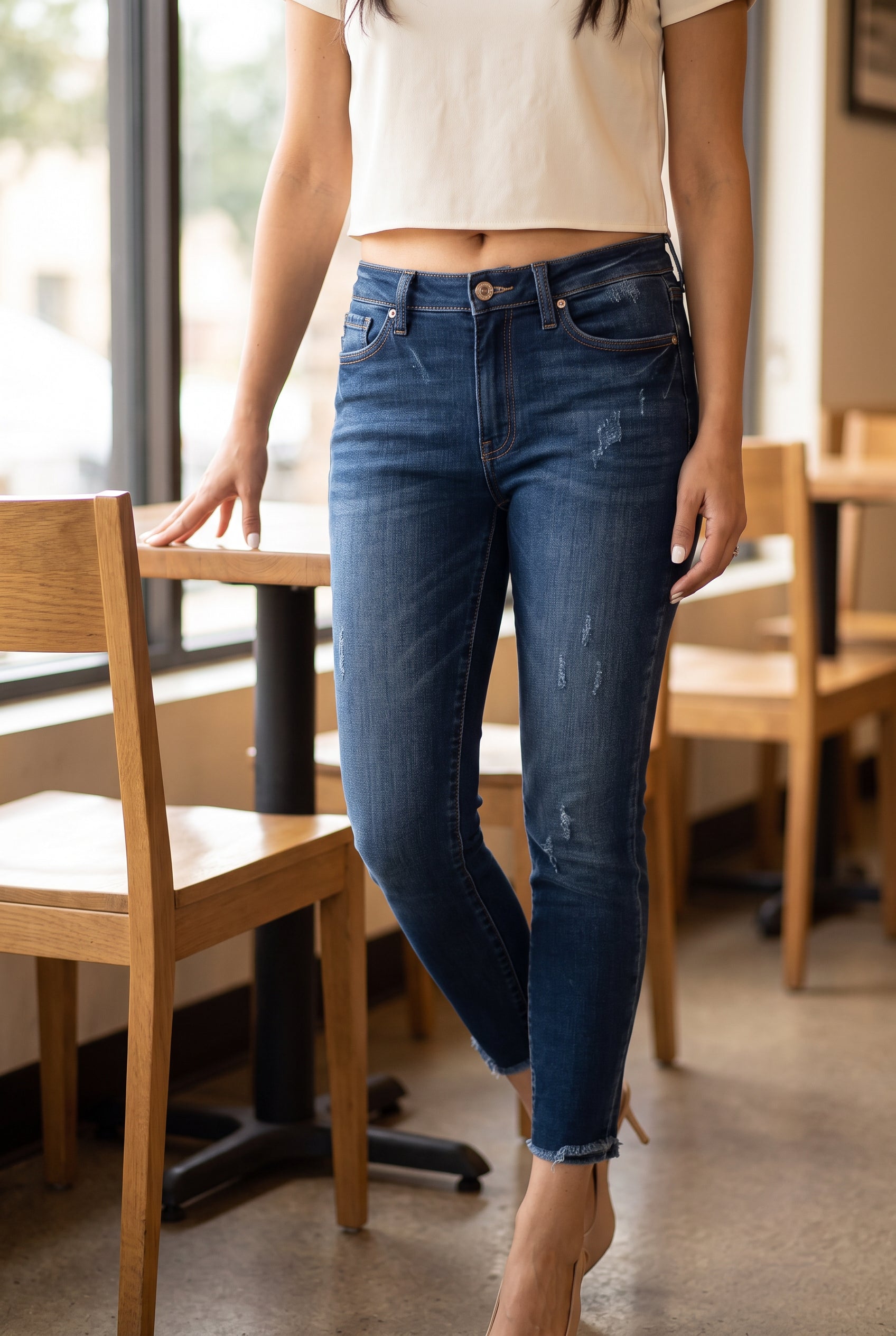 Beautiful Day Mid Rise Ankle Jeans styled with heels beside a café table for a polished casual look.