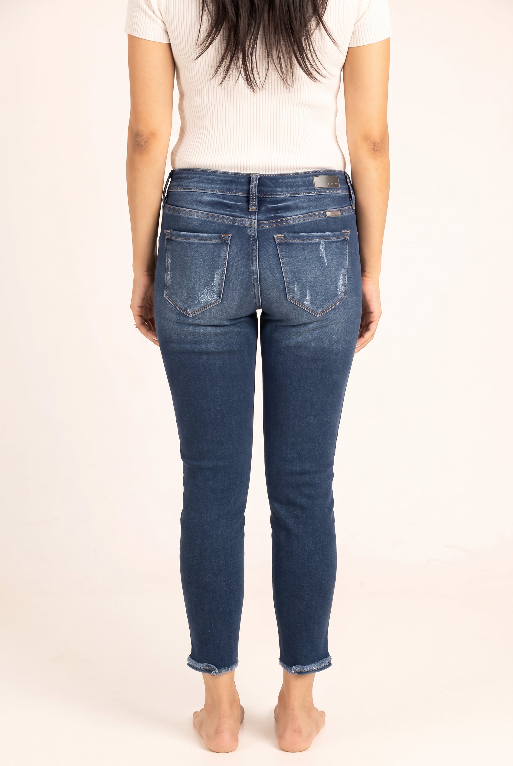Back view of Beautiful Day Mid Rise Ankle Jeans showing the yoke, patch pockets, seat fit and raw hems.