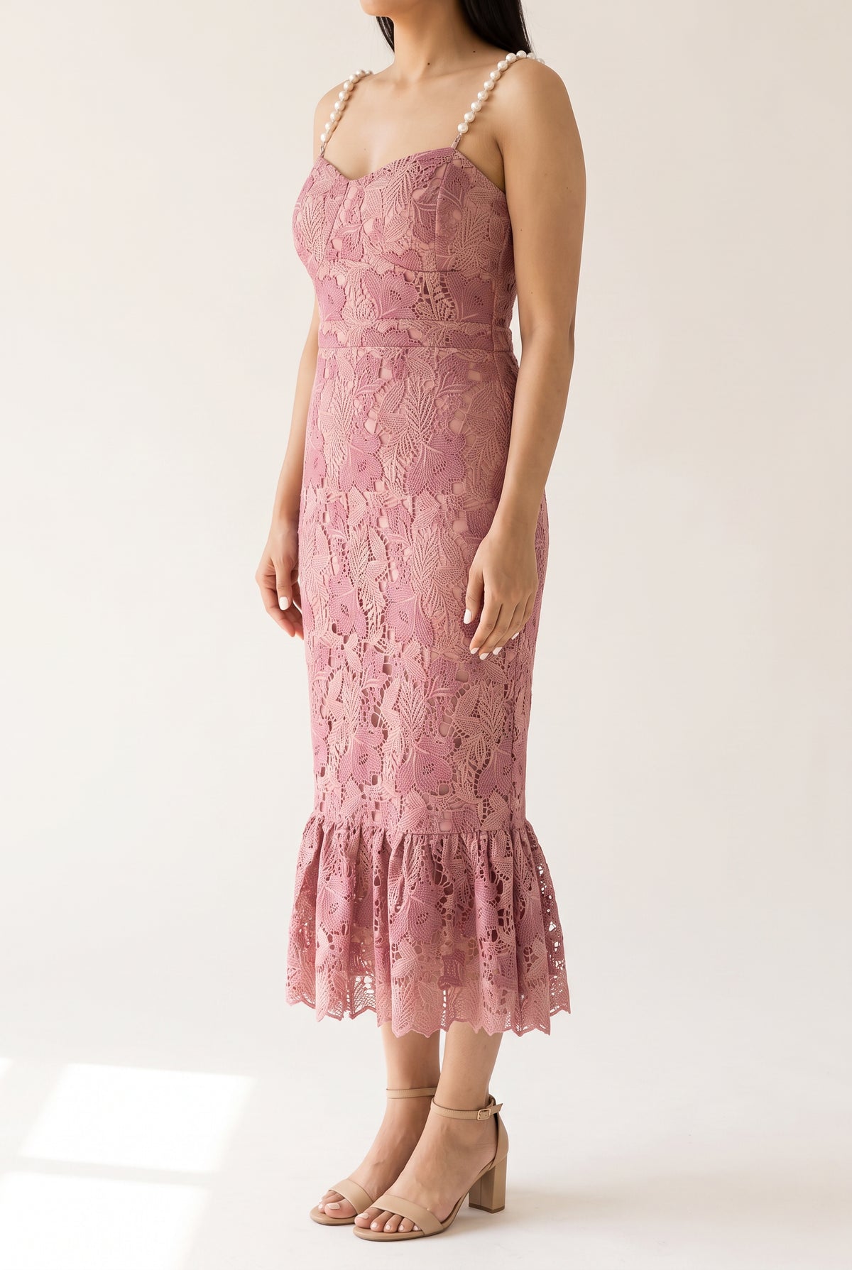 Angled side view of the pink lace mermaid dress showing its close fit and low flounce.