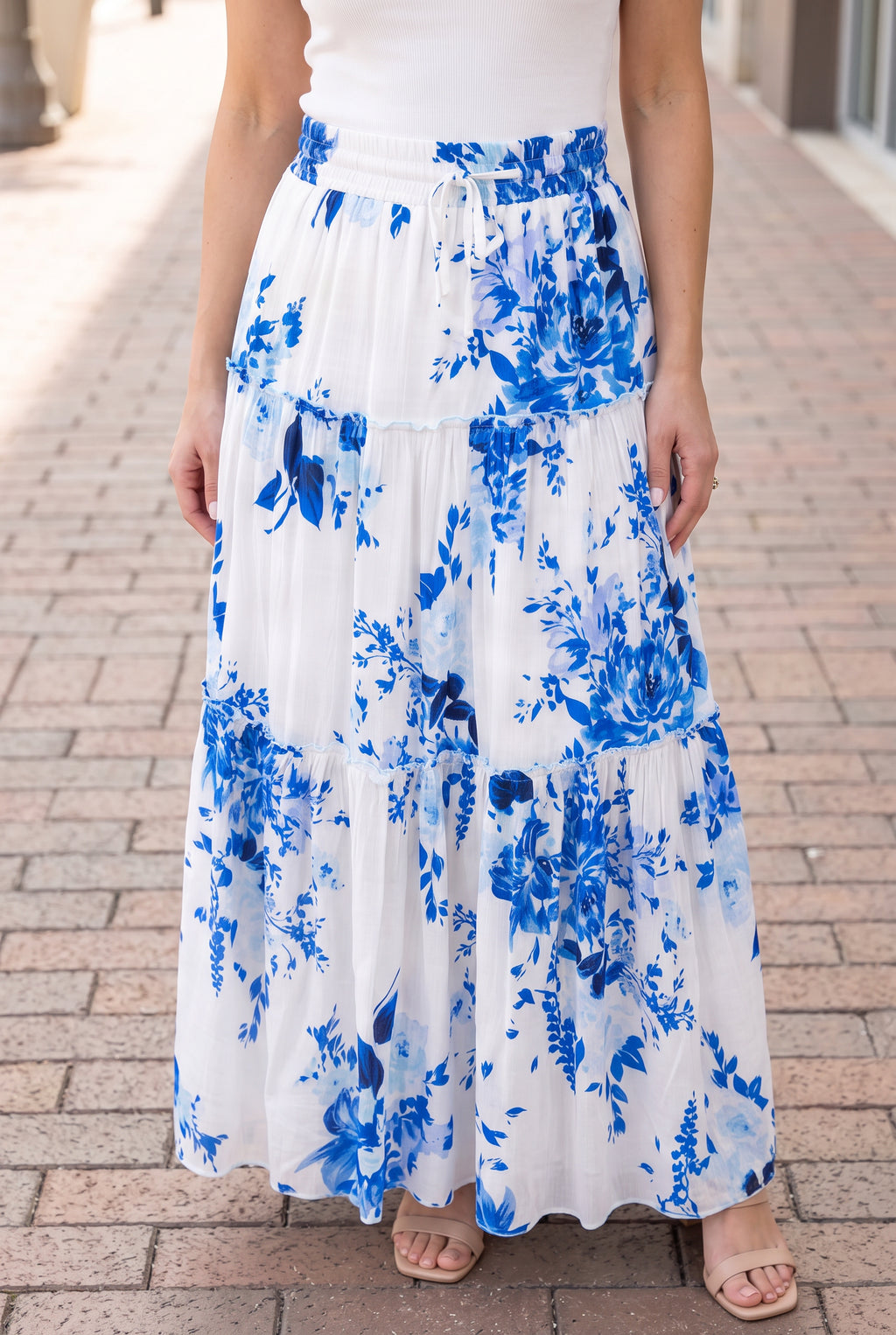 Close view of the blue floral maxi skirt’s smocked waist, drawstring and ruffled tier seam.
