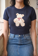 Seated café fit of the navy teddy bear sweater top showing how the cropped hem rests at the waistband.