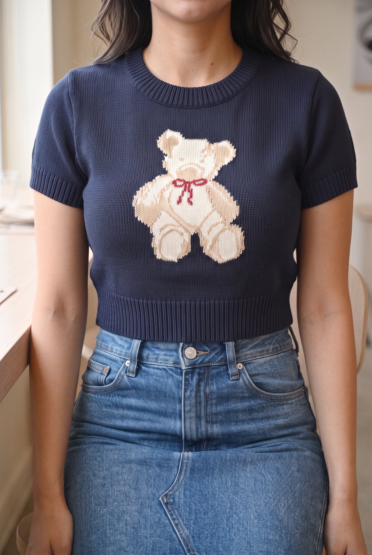 Seated café fit of the navy teddy bear sweater top showing how the cropped hem rests at the waistband.