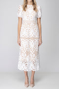 Front fit of the white crochet lace midi dress showing its waist, A-line skirt and scalloped hem.