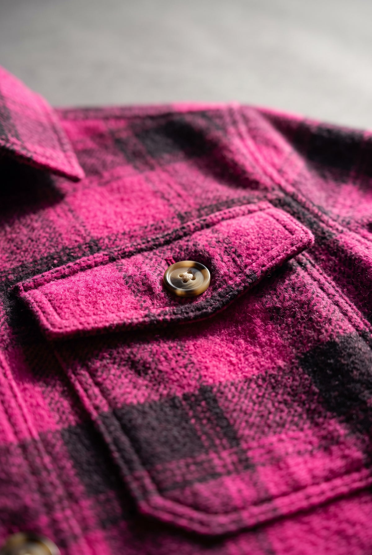 Close detail of the Berry Blessed Plaid Shacket fabric, stitching and marbled button.