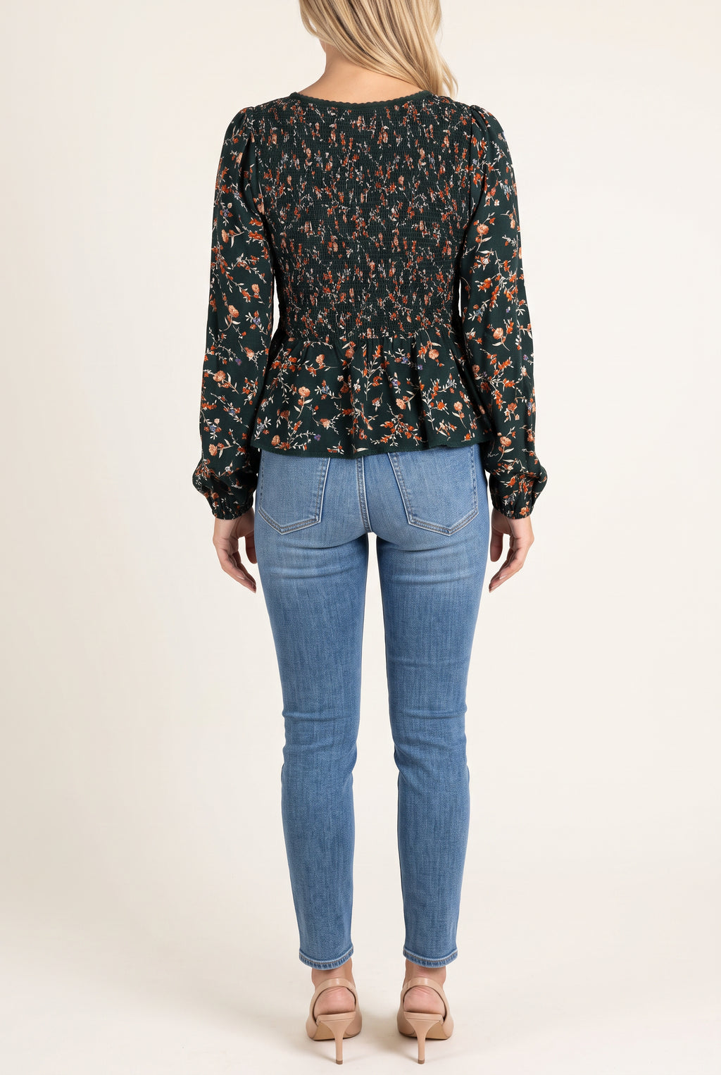 Back fit of the floral top showing the full smocked back, long sleeves and peplum hem.