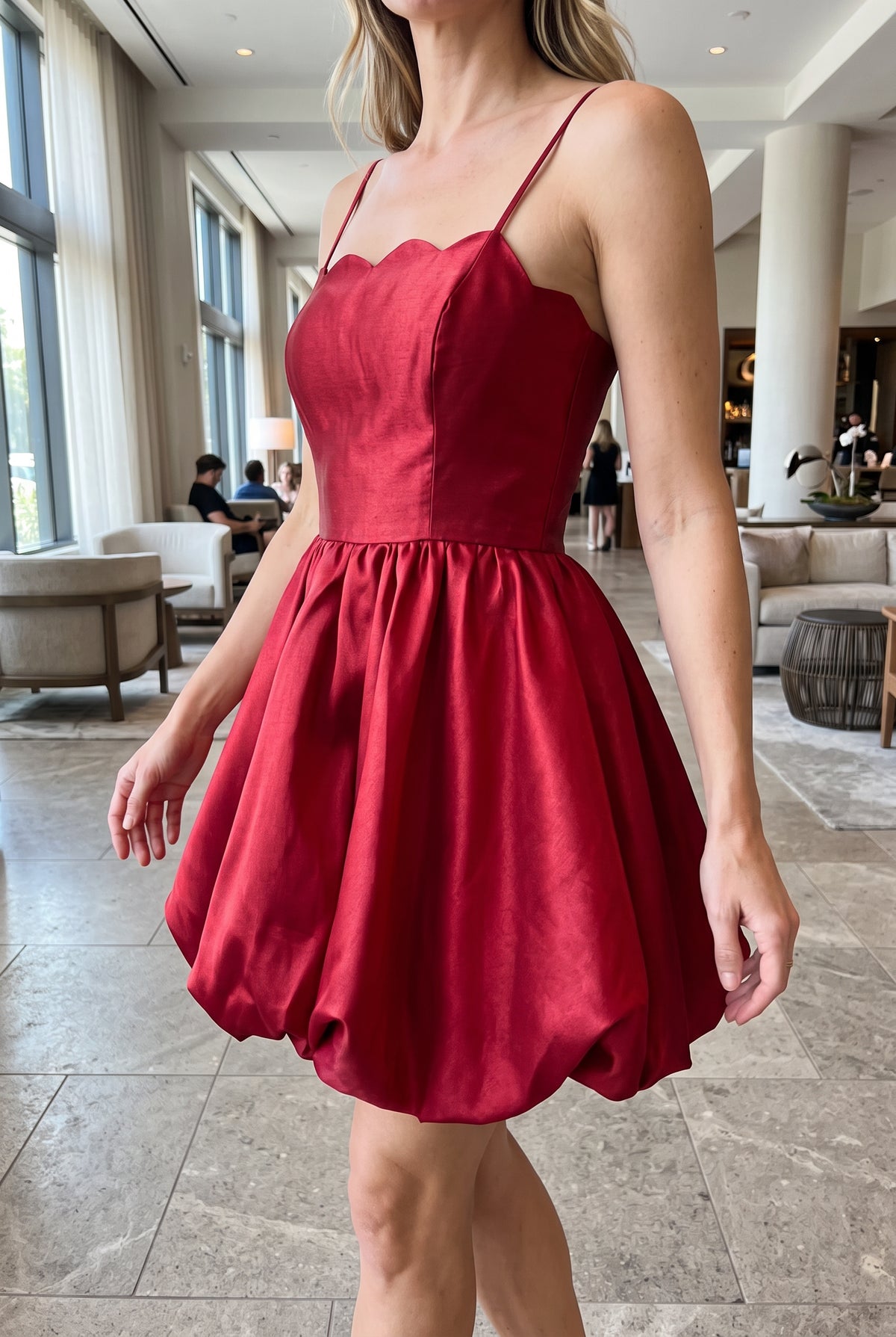 Angled side fit of the red bubble mini dress showing its fitted bodice and rounded skirt projection.