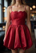 Close view of the red dress showing its scalloped neckline, fine straps, bodice seams and satin sheen.