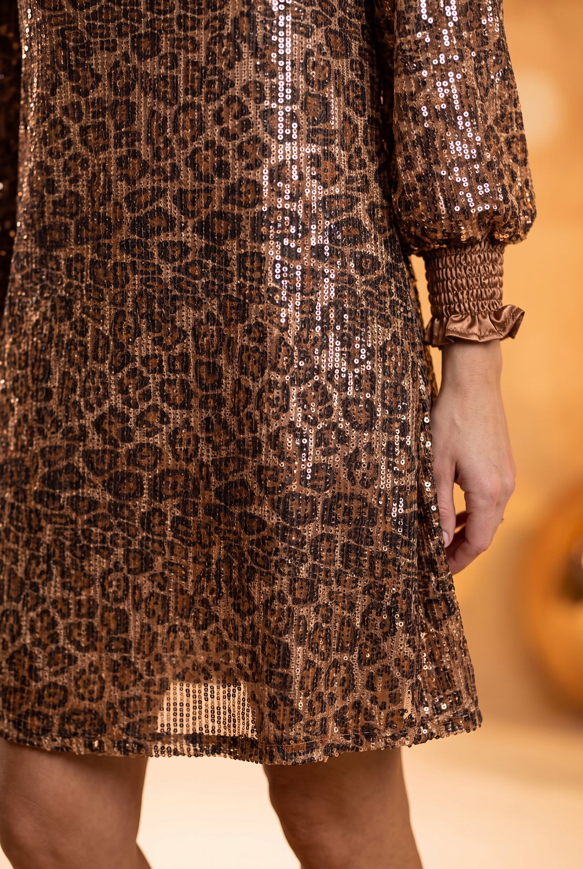 Detail of the Going Wild dress showing leopard sequins, smocked cuff, sheer outer hem, and shorter lining.