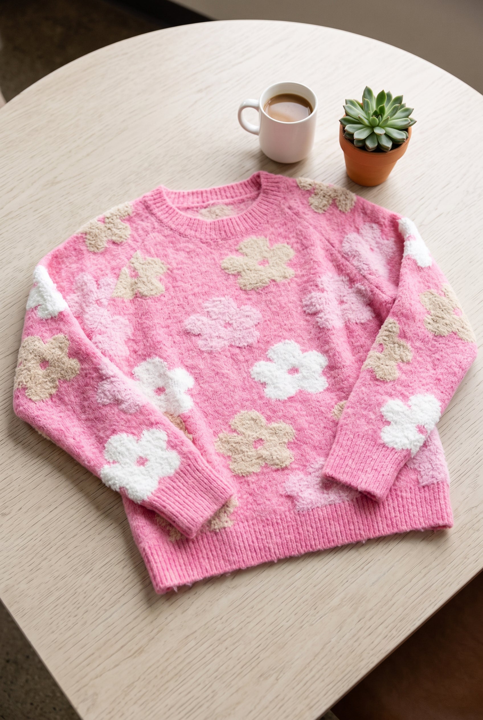 Everly Floral Sweater Top in Pink laid flat to show its relaxed body, dropped shoulders, sleeves and ribbed hem.