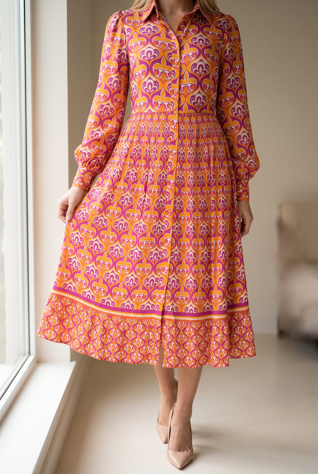 Close view of the shirt dress skirt showing its gathered waist, border print, lower tier and fluid folds.
