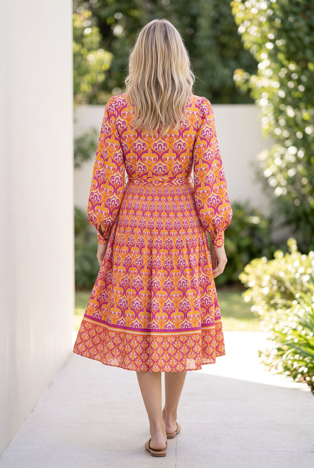 Back walking view of the Small shirt dress showing the waist tie, bishop sleeves and moving tiered skirt.