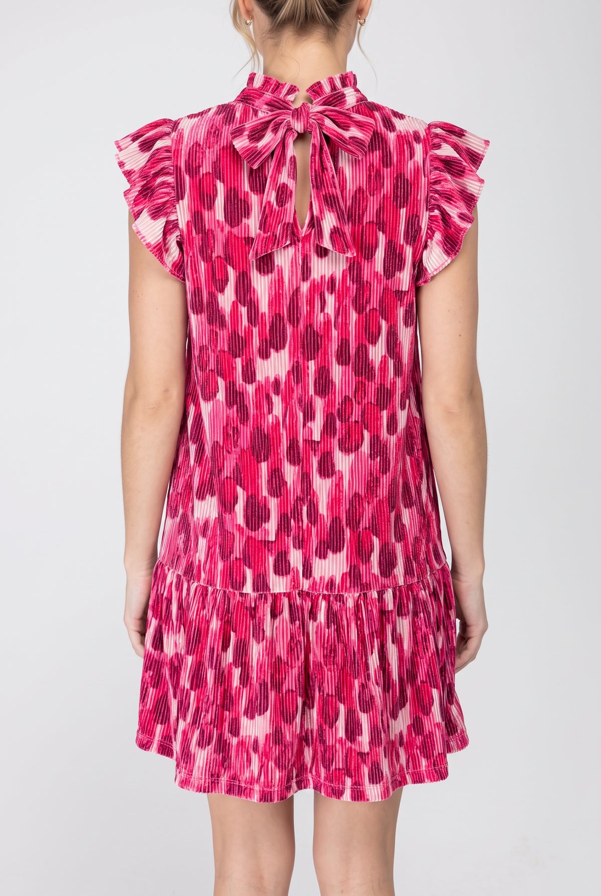 Back view of the pink pleated velvet shift dress showing the self-tie bow and keyhole opening.