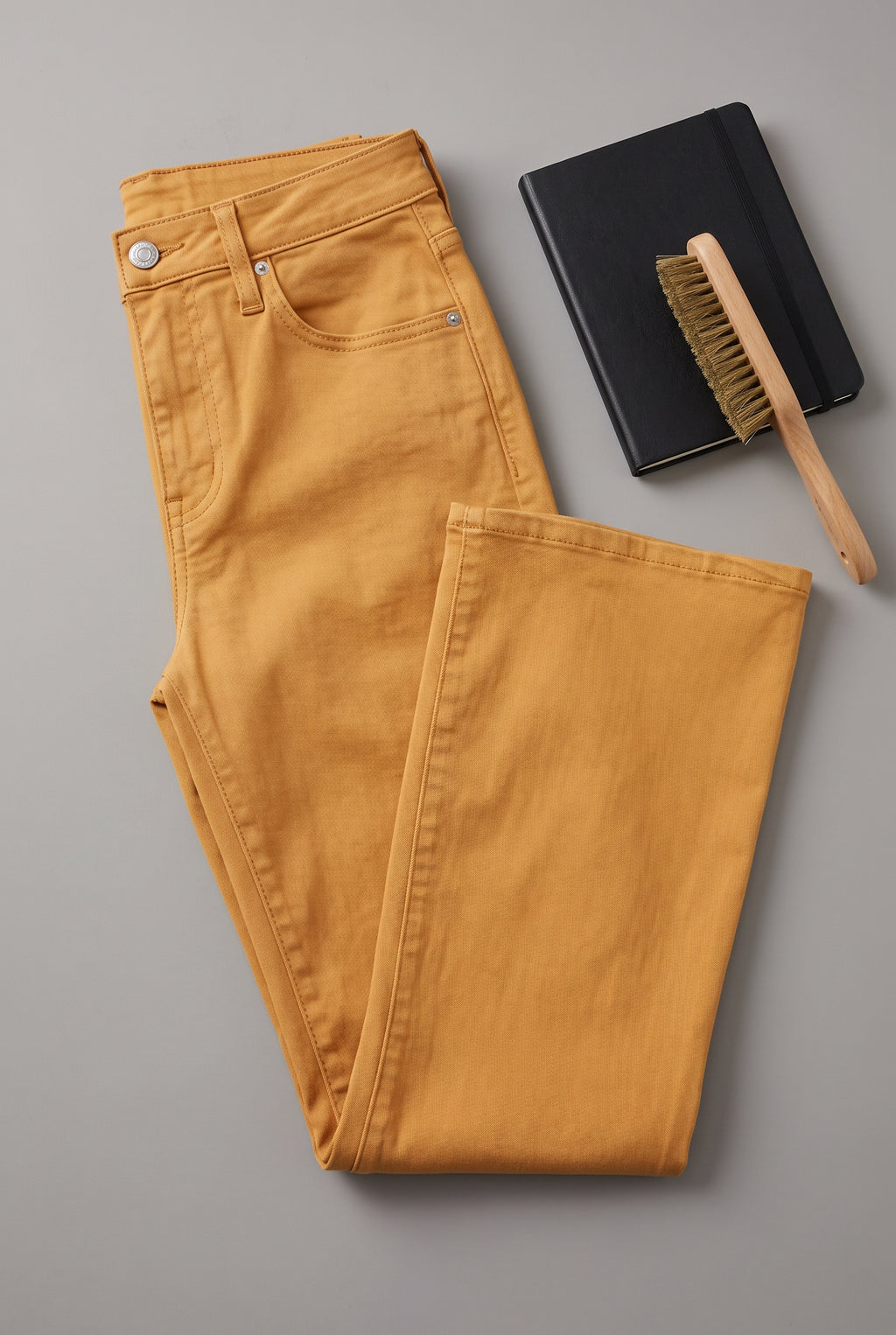 Gold kick-flare pants detail showing the denim texture, waistband hardware, stitching and raw-cut hem.