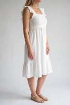 Angled side fit of the white crochet dress showing the ruffled strap and raised waist.
