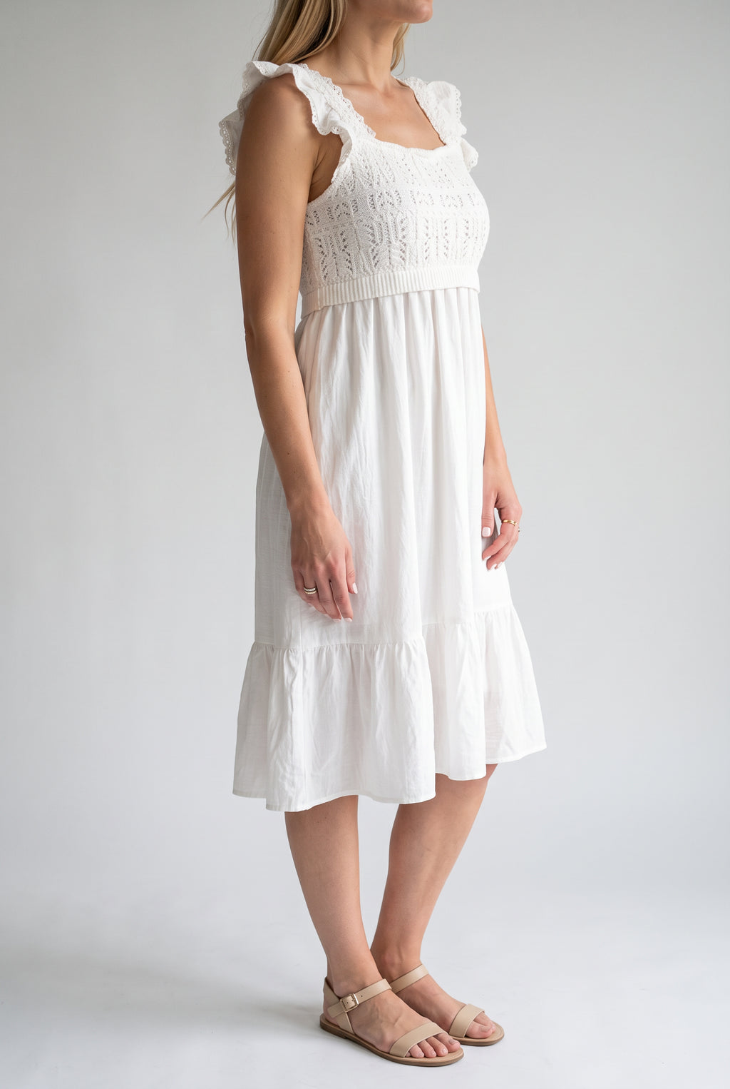 Angled side fit of the white crochet dress showing the ruffled strap and raised waist.