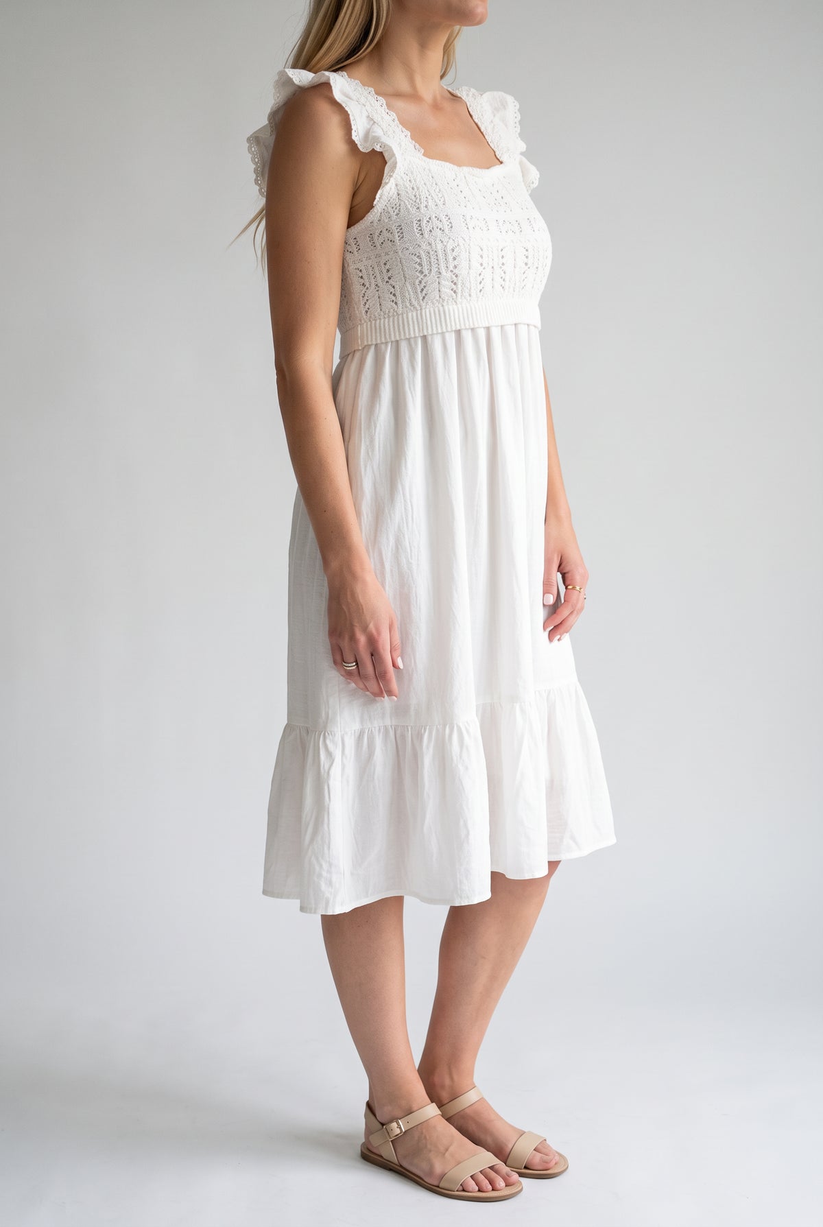 Angled side fit of the white crochet dress showing the ruffled strap and raised waist.
