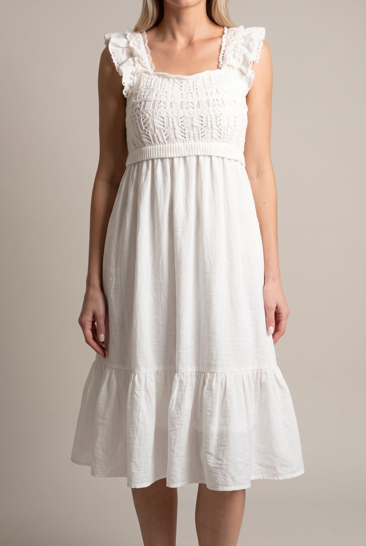Front fit of the white crochet midi dress showing its empire waist and tiered skirt.