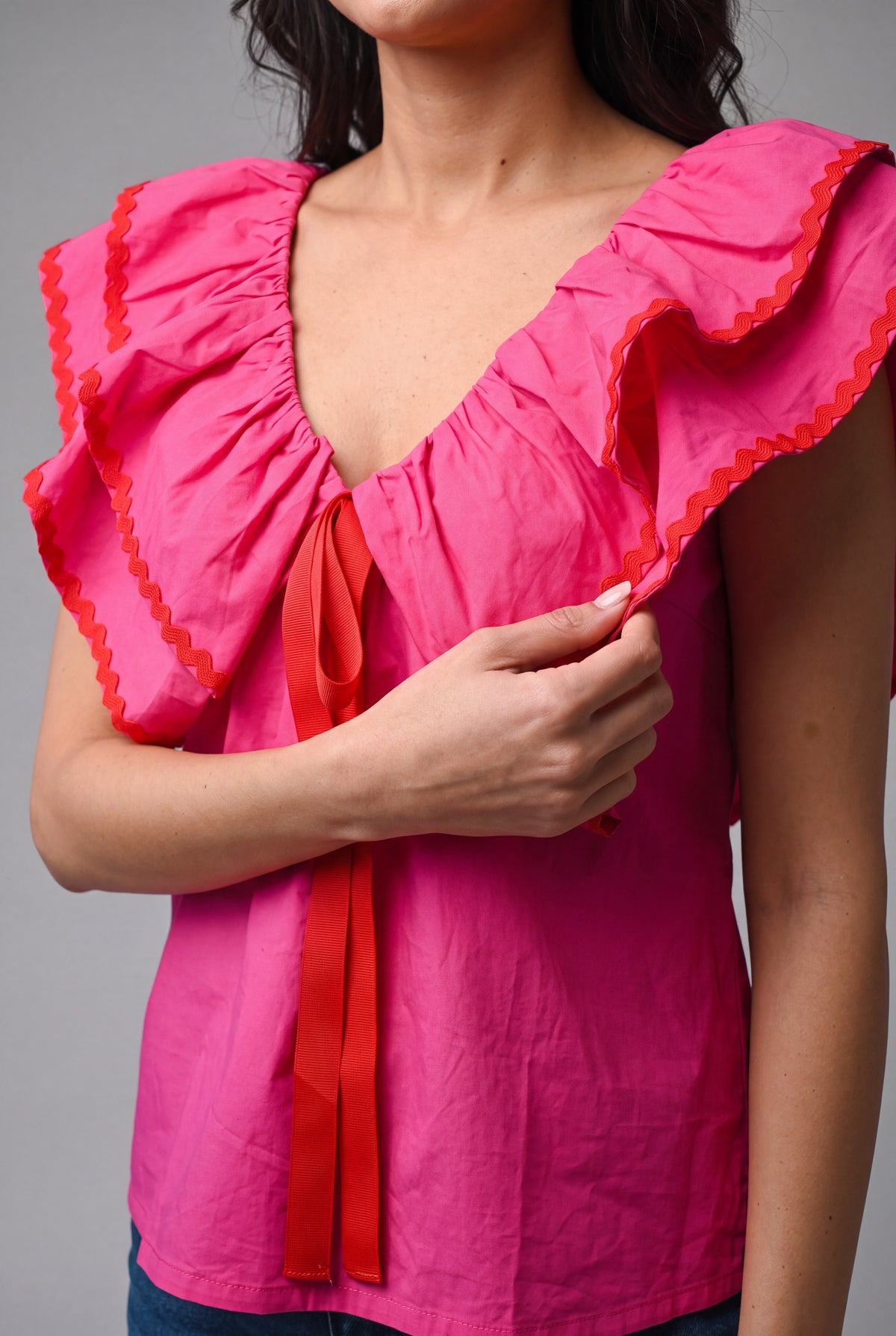 Close detail of the pink cotton ruffles, red ricrac trim, and ribbon tie on the babydoll top.
