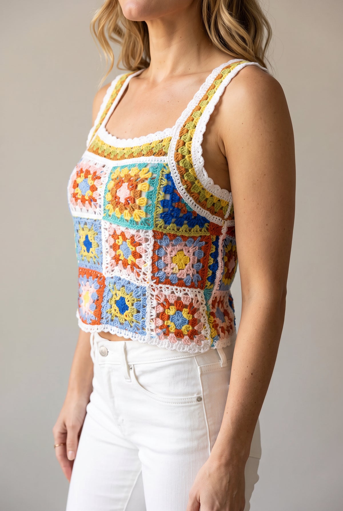 Angled side view of the crochet tank showing the open armhole, bust fit and cropped hem.