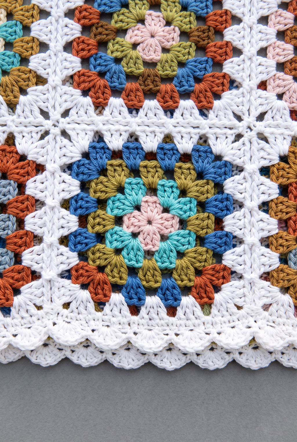 Close detail of the tank’s colorful crochet motifs, joined open stitches and white scalloped trim.