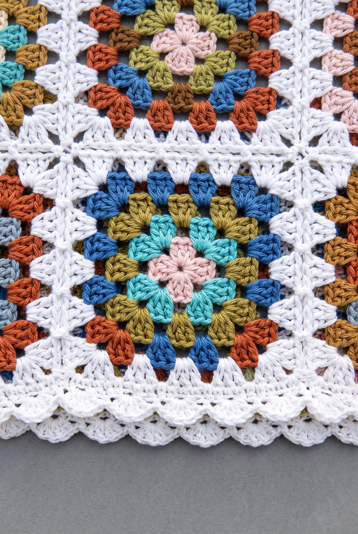 Close detail of the tank’s colorful crochet motifs, joined open stitches and white scalloped trim.