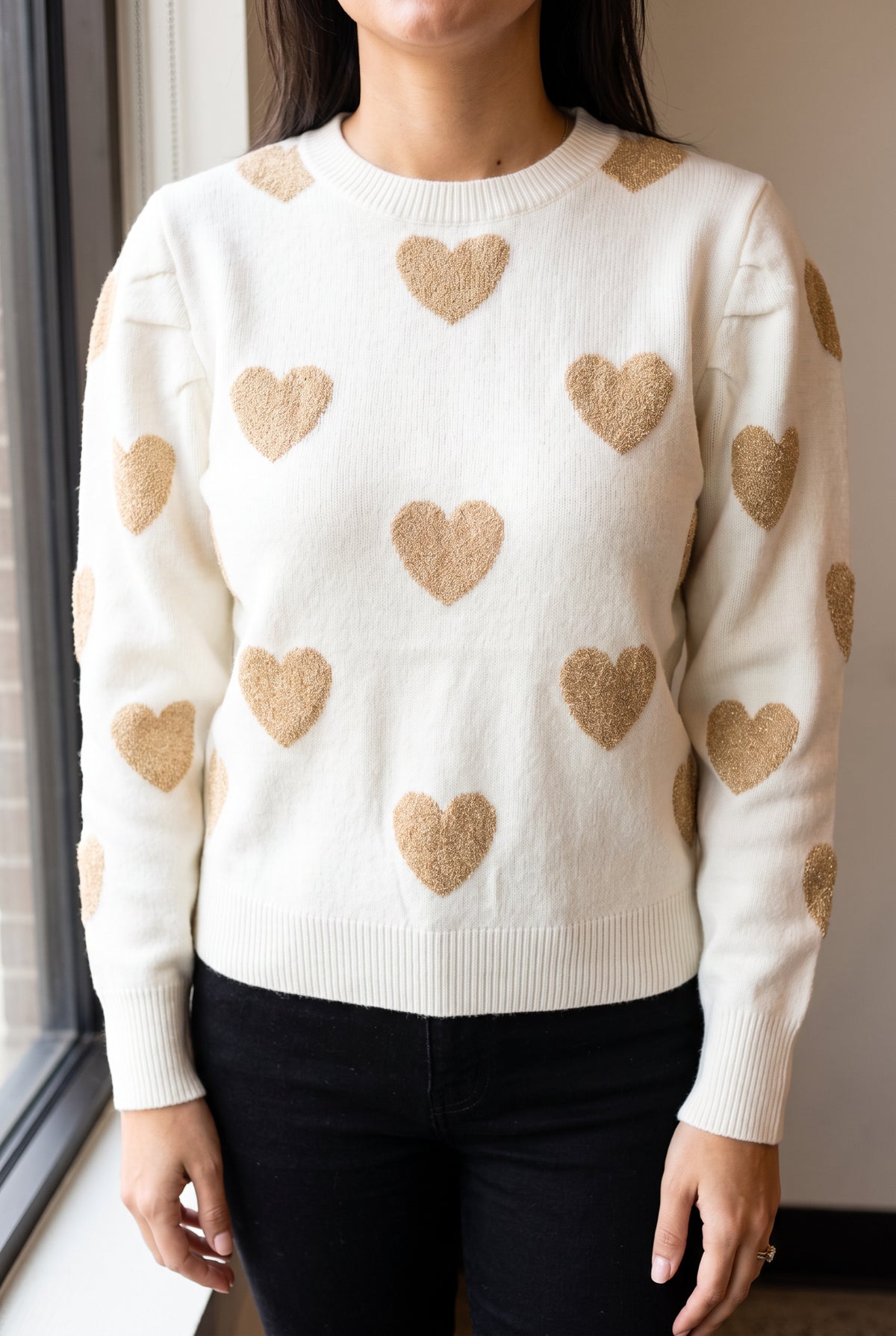 Daylight detail of the Make Me Feel Golden Heart Sweater showing its ivory knit and metallic gold hearts.