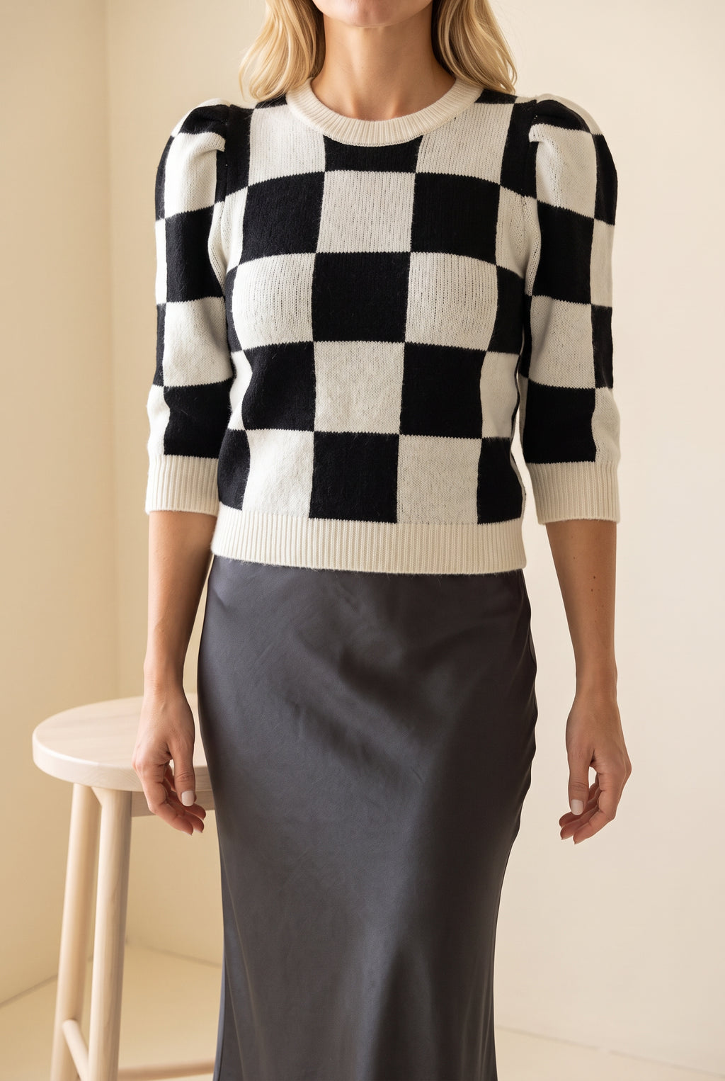 Checkmate Chic checkerboard sweater styled with a satin skirt for a polished everyday outfit.