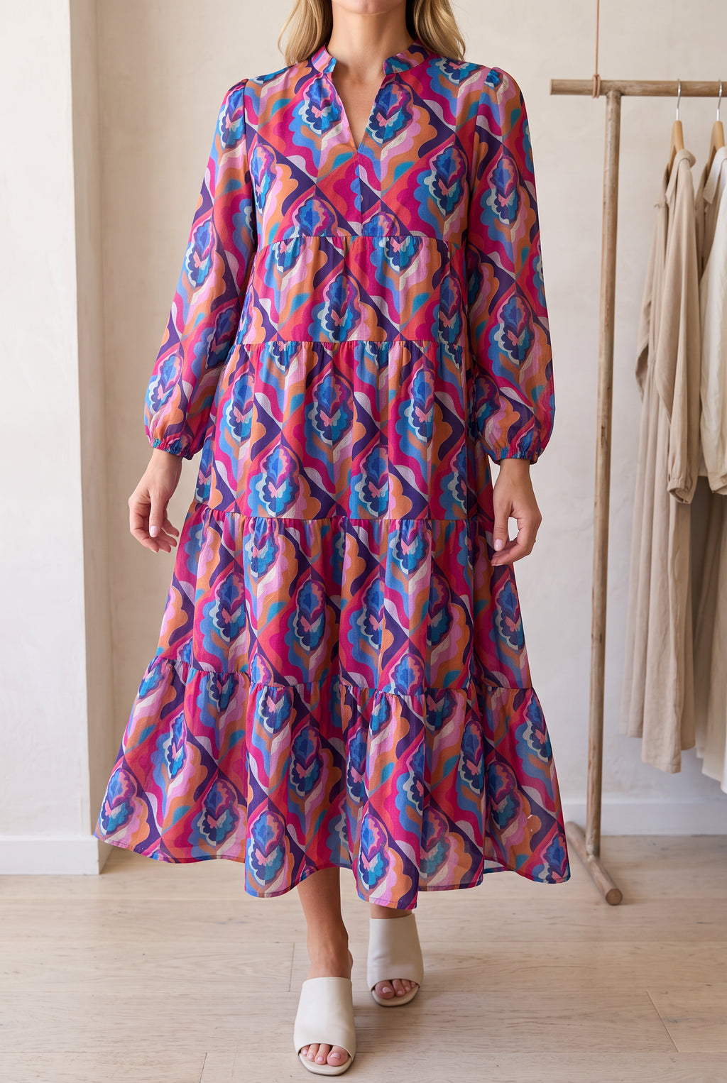 Calling You Small Blue maxi dress worn in a bright boutique, showing its colourful print and flowing tiers.