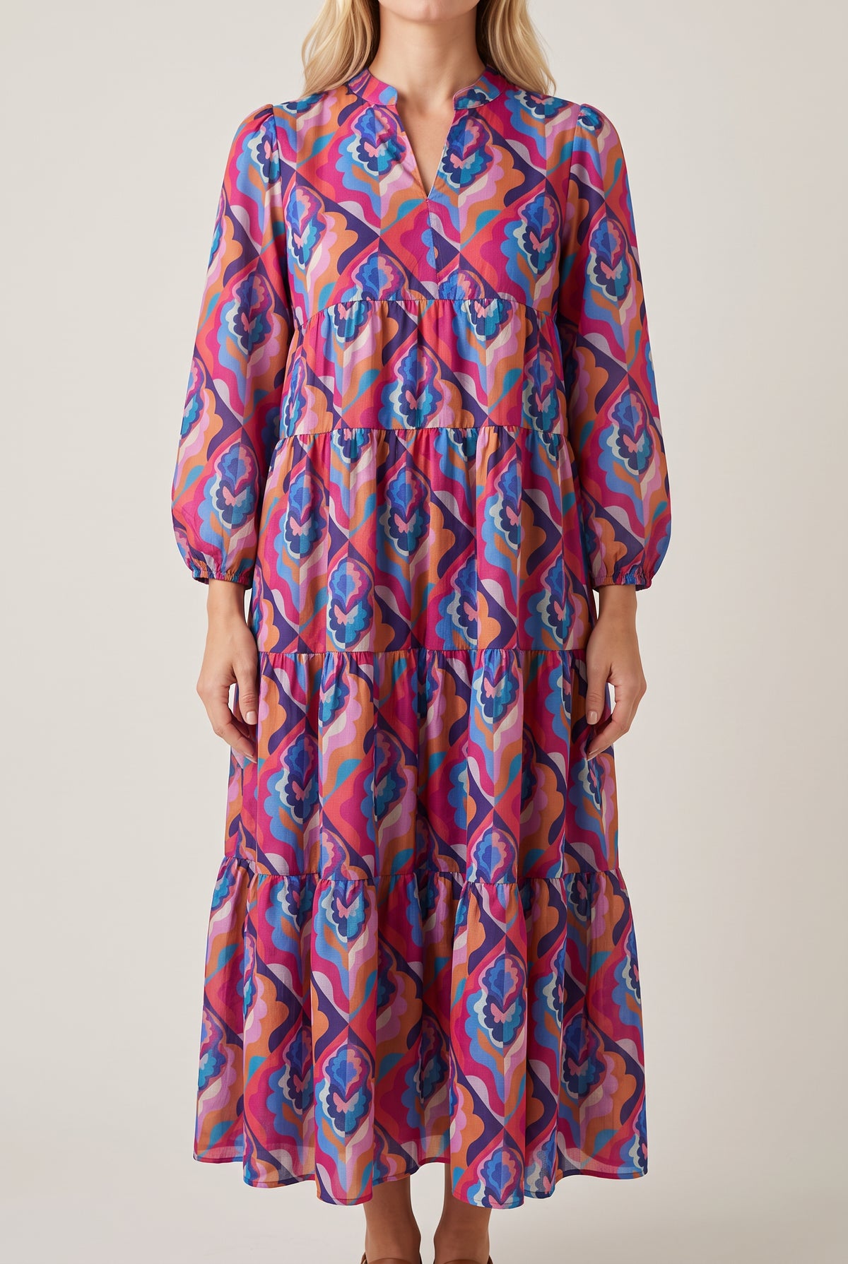 Front view of the Calling You long sleeve tiered dress in a retro magenta and blue geometric print, with split neckline and balloon sleeves.