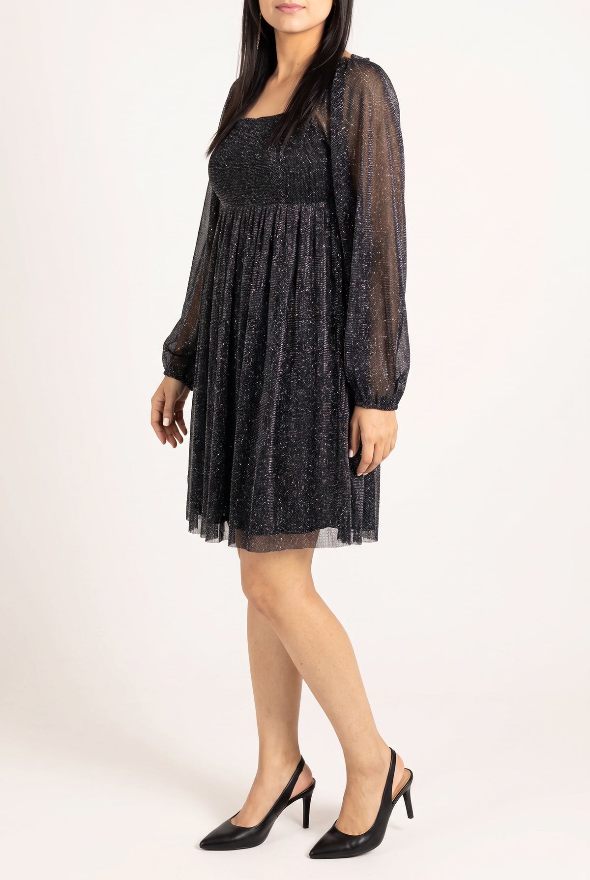 Angled side fit of the black glitter babydoll dress showing sleeve volume and skirt projection.