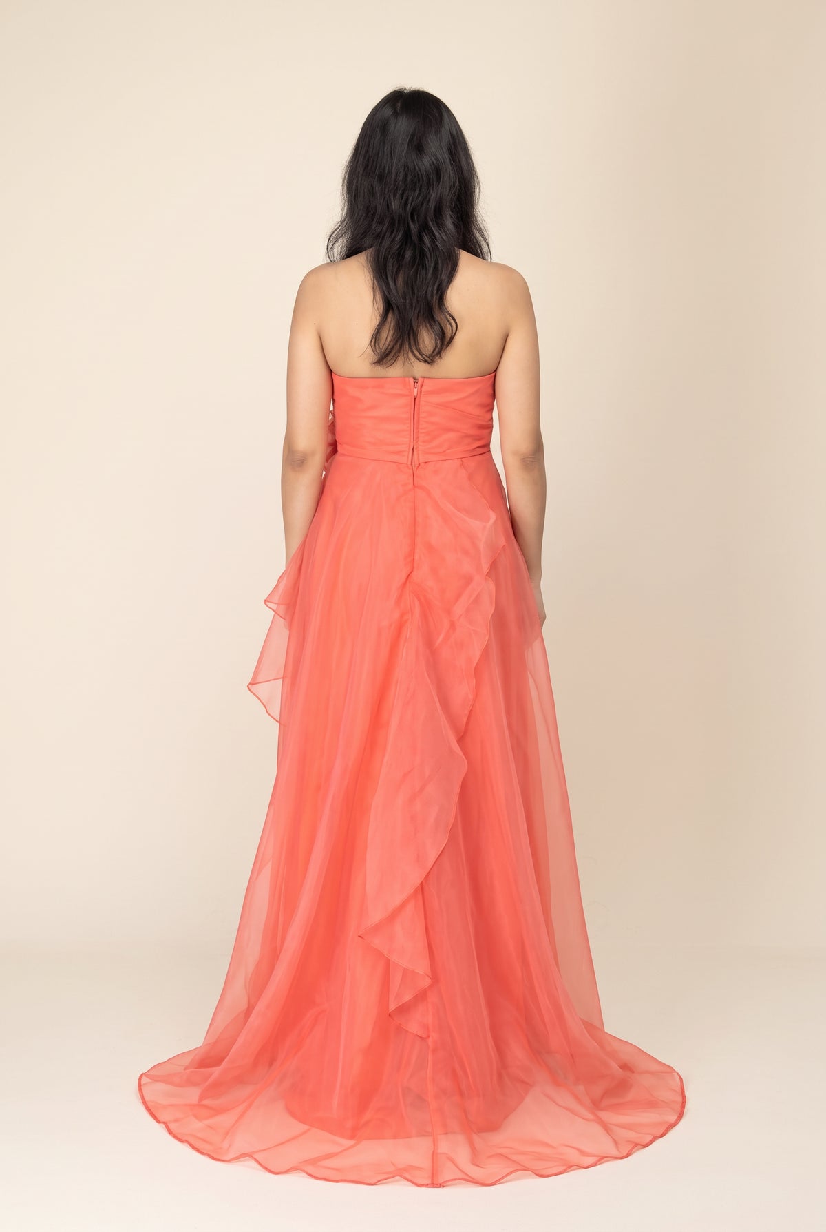 Complete back view of the coral organza maxi dress showing the zipper, back neckline and trailing layered hem.