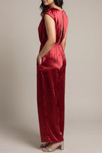 Angled view of the I'm Yours red satin jumpsuit showing its cap sleeve, pocket and wide-leg drape.