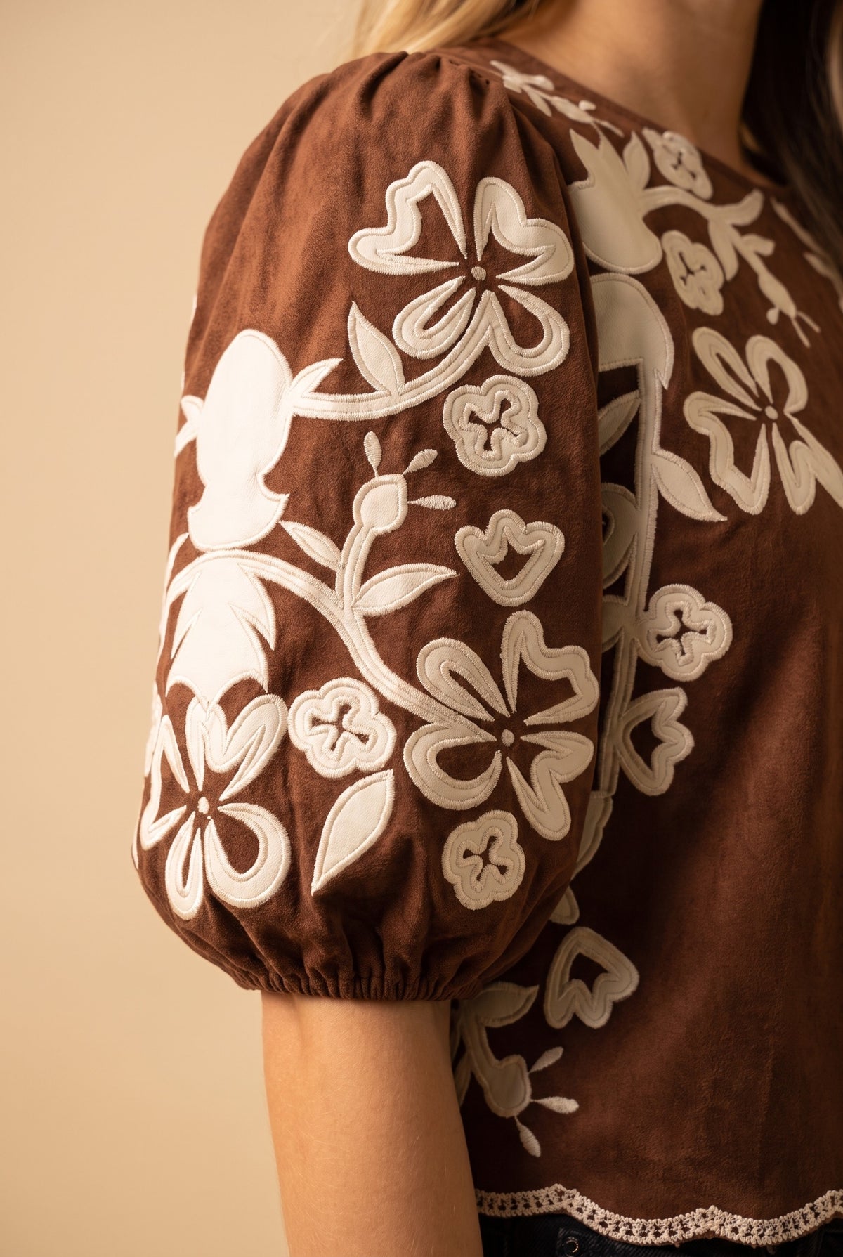 Close-up of the brown embroidered faux suede top showing the fabric and finishing details.