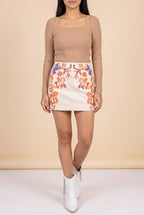 Front view of the cream embroidered faux suede mini skirt showing the fit and length.