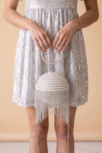 The Lola pearl rhinestone fringe ball bag carried at the hip.