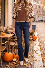 The embroidered suede top styled with dark indigo flare jeans, cream western booties and a delicate pearl chain necklace on a fall café terrace.