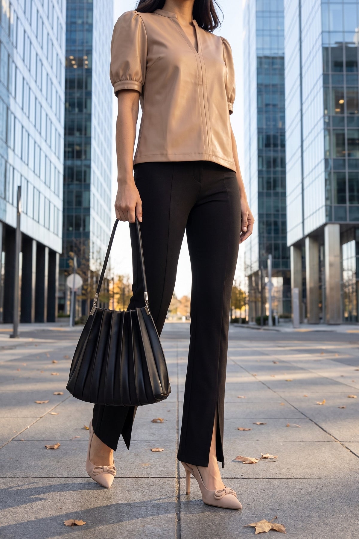 The latte faux leather top styled with black slit-front flare trousers, nude bow slingback pumps and a black pleated shoulder bag for the office.