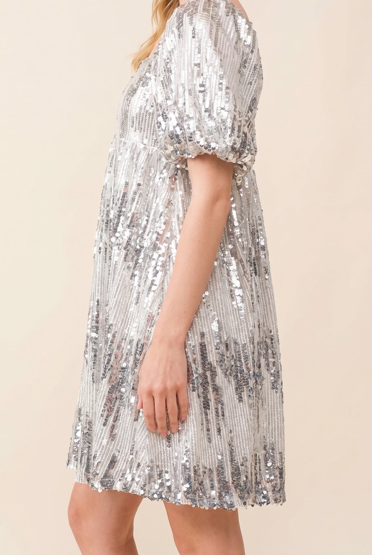 Side view of the sequin babydoll dress showing the puff sleeve and loose babydoll skirt