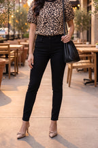 The taupe leopard puff sleeve top styled with black high-rise skinny jeans, nude bow slingback pumps and a black pleated shoulder bag.