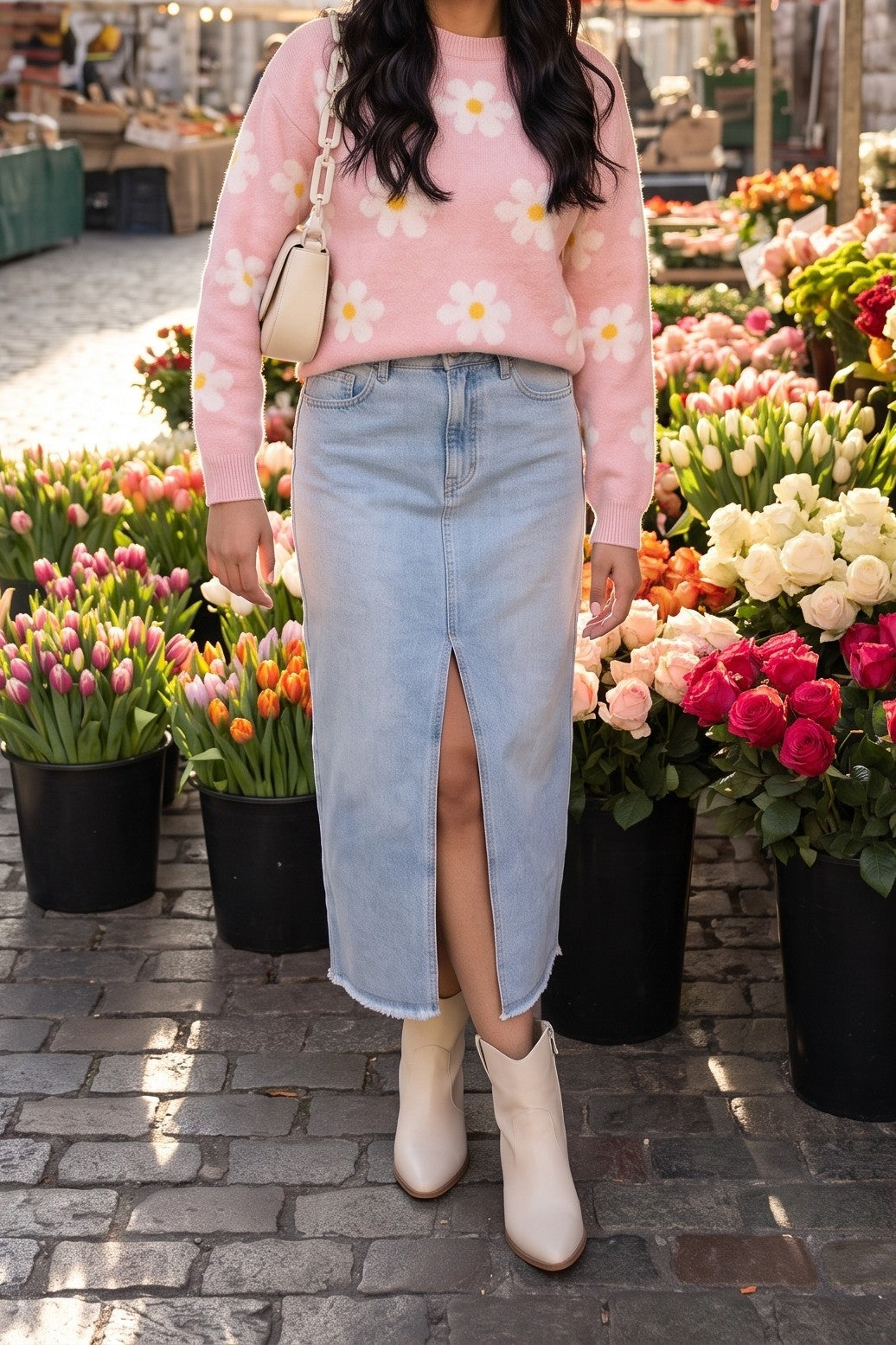 The pink daisy sweater styled with a light-wash denim midi skirt, cream western booties and a cream chain-strap shoulder bag for an easy weekend at the flower market.
