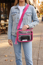Joanna Cross Body Camera Bag in Fuchsia worn crossbody on its solid hot pink strap, phone and lip balm visible through the clear body
