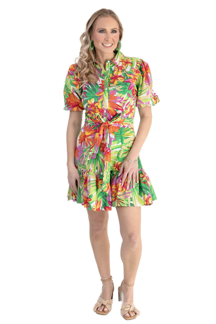 A model wearing a vibrant tropical floral print puff sleeve shirt dress with a self-tie waist and ruffle hem, perfect for vacations and summer outings.