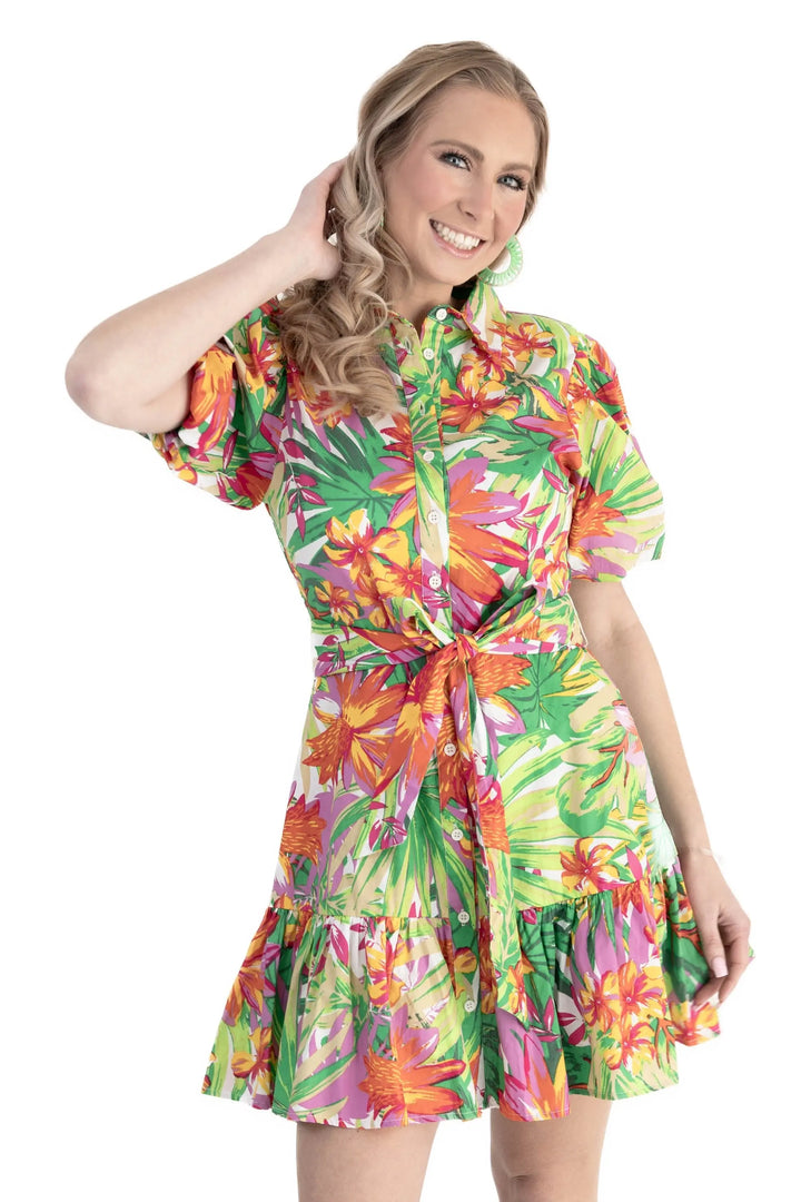 A model wearing a vibrant tropical floral print puff sleeve shirt dress with a self-tie waist and ruffle hem, perfect for vacations and summer outings.