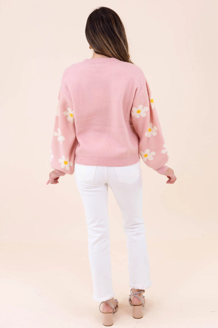 Blush pink knit sweater with white daisy floral pattern, featuring a crew neckline and balloon sleeves for a cozy and stylish look.