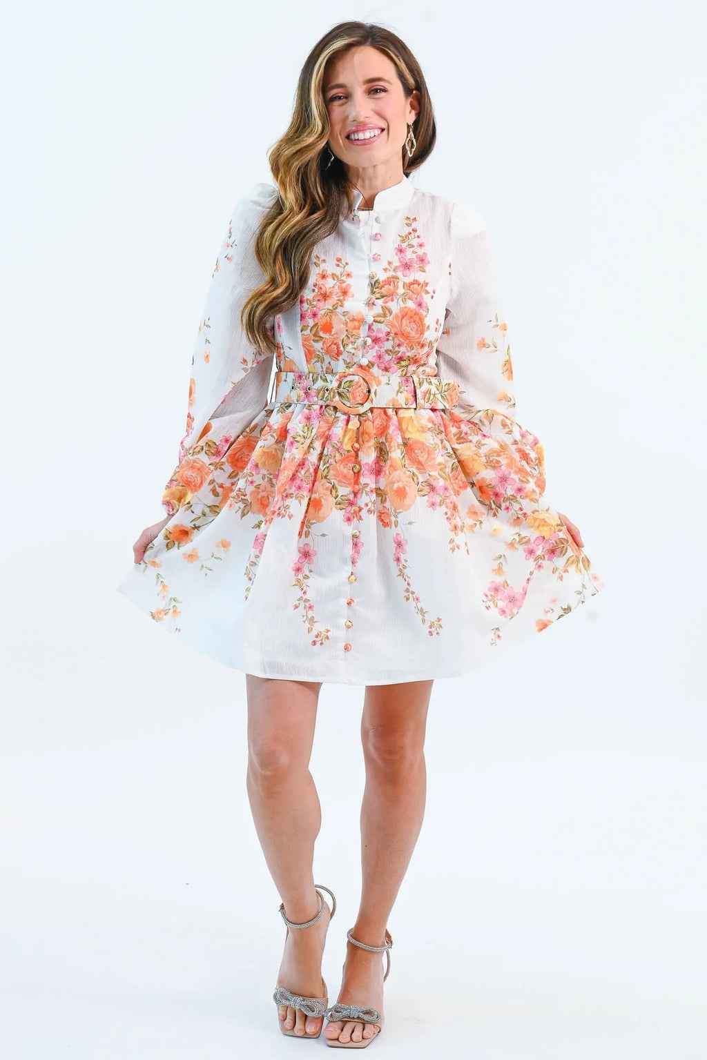 A woman wearing a floral chiffon mini dress with puff sleeves, a belted waist, and a button-down front, perfect for spring and summer.