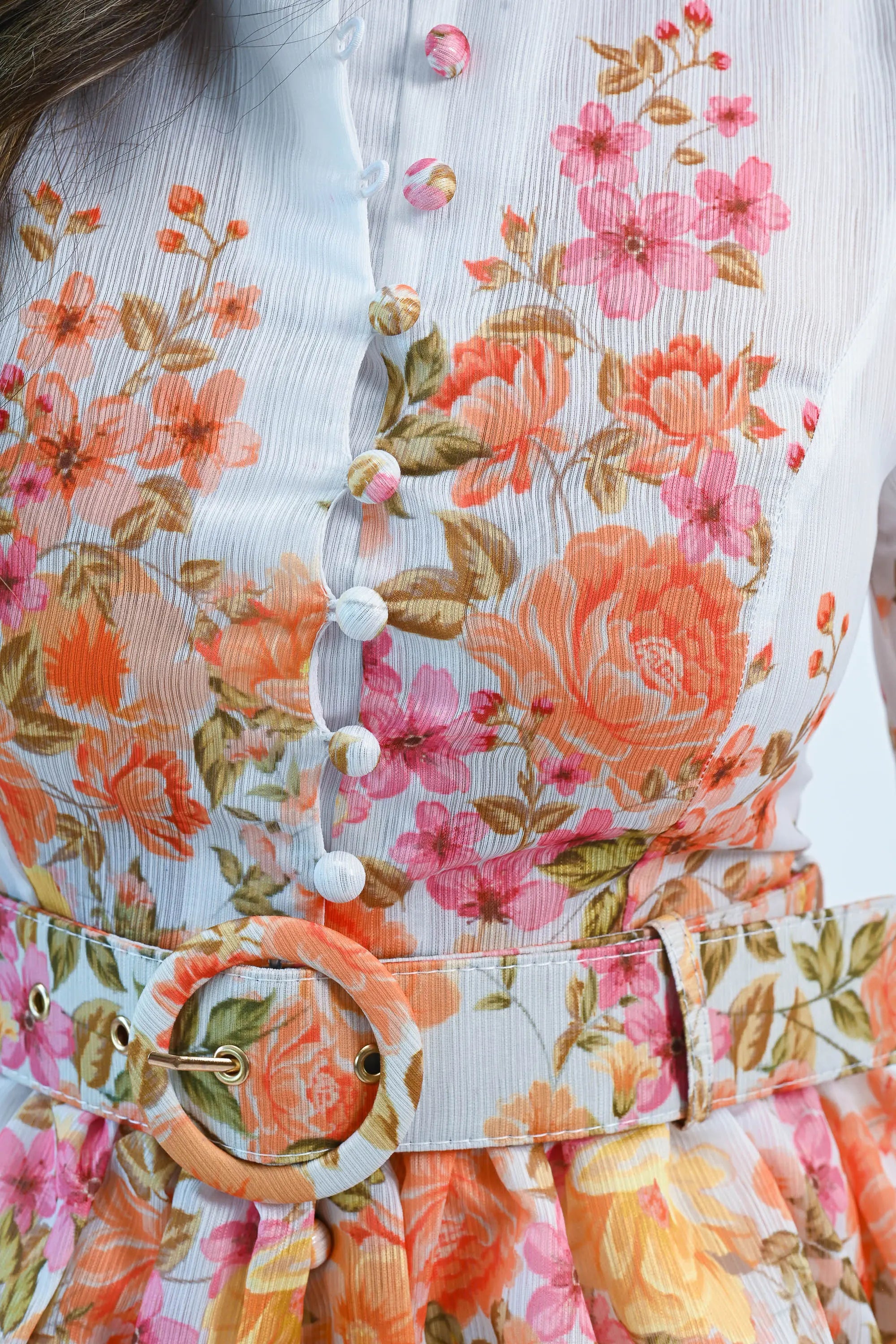 A woman wearing a floral chiffon mini dress with puff sleeves, a belted waist, and a button-down front, perfect for spring and summer.