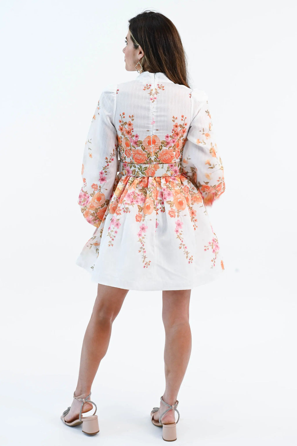 A woman wearing a floral chiffon mini dress with puff sleeves, a belted waist, and a button-down front, perfect for spring and summer.