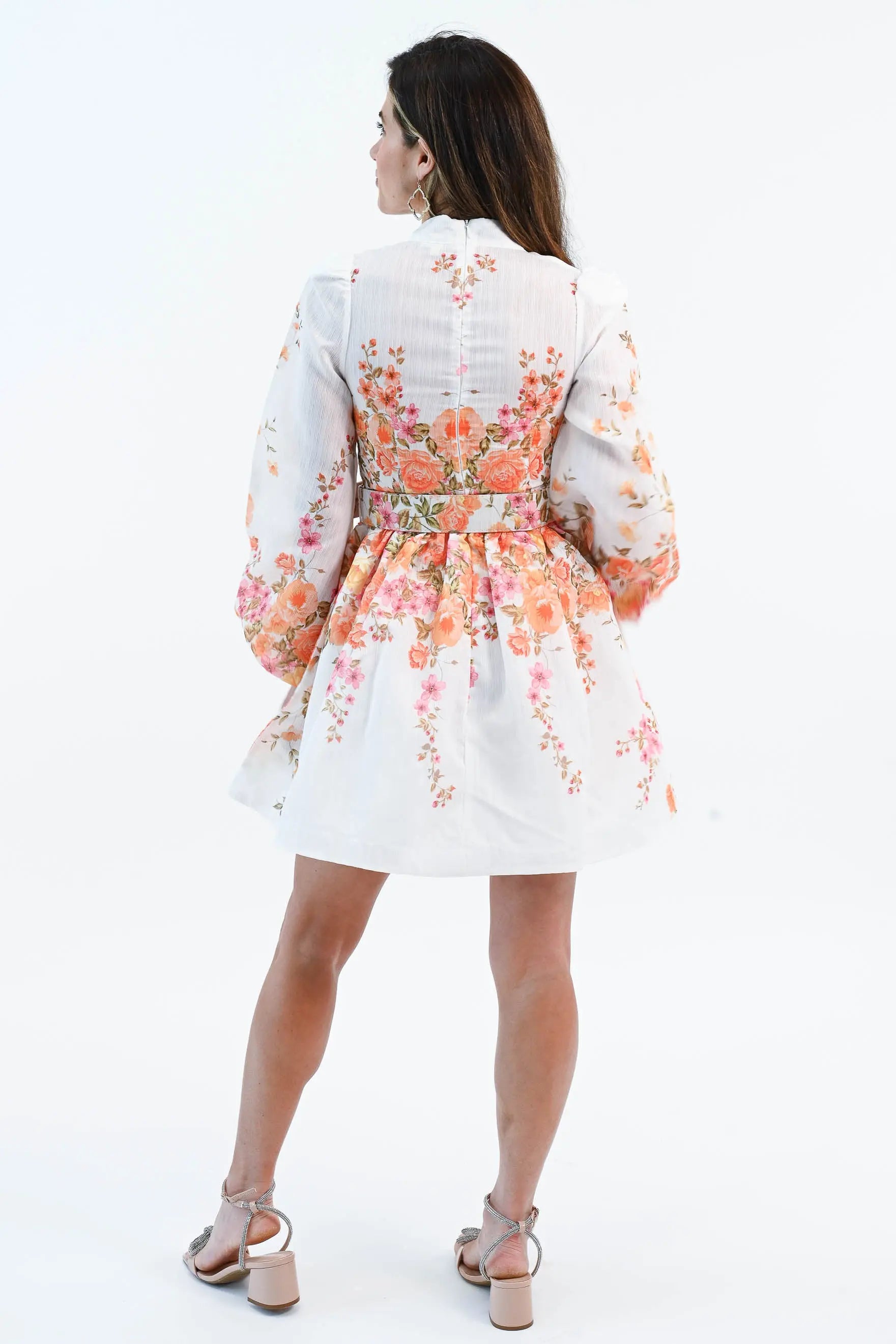 A woman wearing a floral chiffon mini dress with puff sleeves, a belted waist, and a button-down front, perfect for spring and summer.
