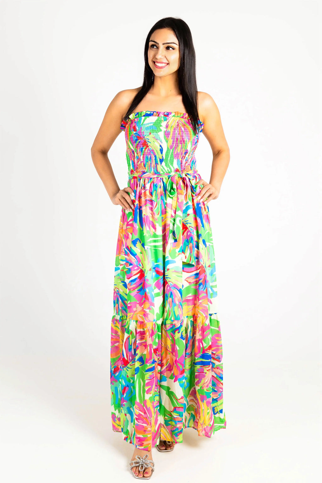 A woman wearing a vibrant tropical-print strapless maxi dress with a smocked bodice and flowy tiered skirt, perfect for summer vacations.